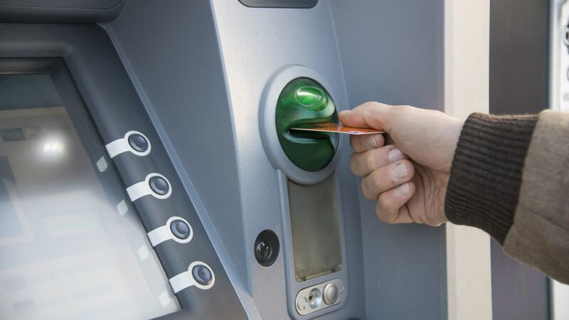 Bankkarte wird in den grünen Schlitz eines Geldautomaten gesteckt