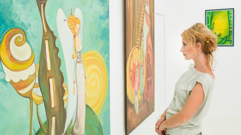 Frau in Kunstgalerie oder Museum betrachtet Bilder einer Ausstellung