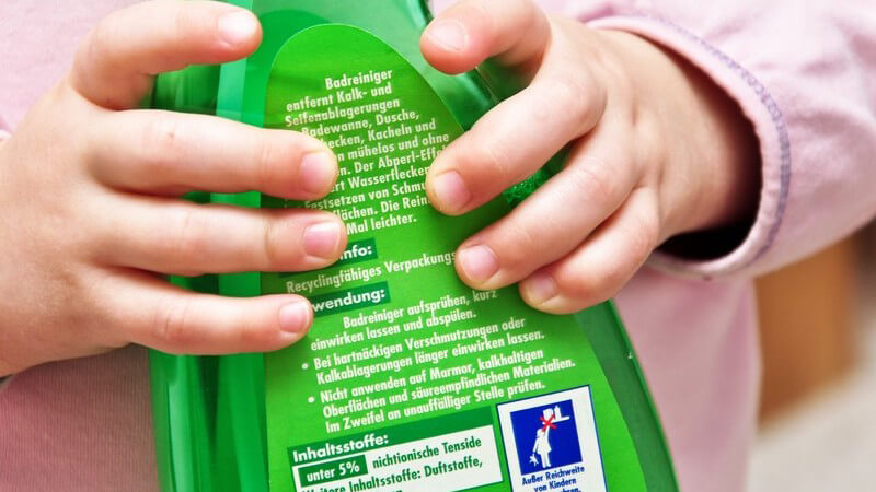 Kinderhände halten eine grüne Flasche mit Reinigunsmittel