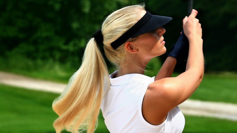 Blonde Frau im Golfoutfit auf Golfplatz