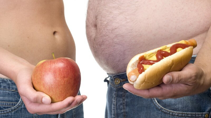 Dicker und dünner Bauch gegenüber, Apfel und Hotdog in den Händen