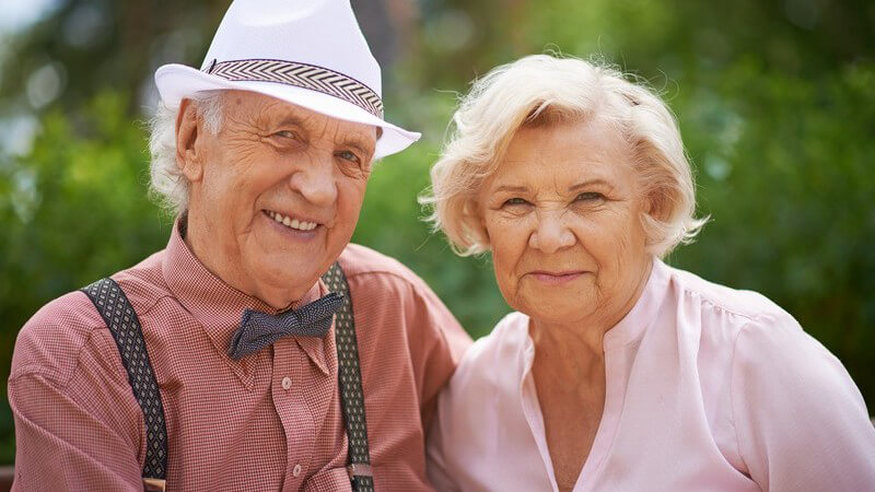 Modisch gekleidetes, lächelndes Seniorenpaar, Mann mit Fliege, Hut und Hosenträgern