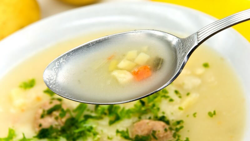 Löffel über Teller mit Kartoffel Creme Suppe mit Fleischbällchen