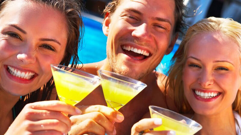 Drei Freunde am Pool mit Cocktail in der Hand