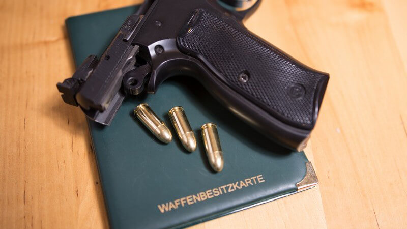 Pistole und drei Patronen liegen auf einer Waffenbesitzkarte