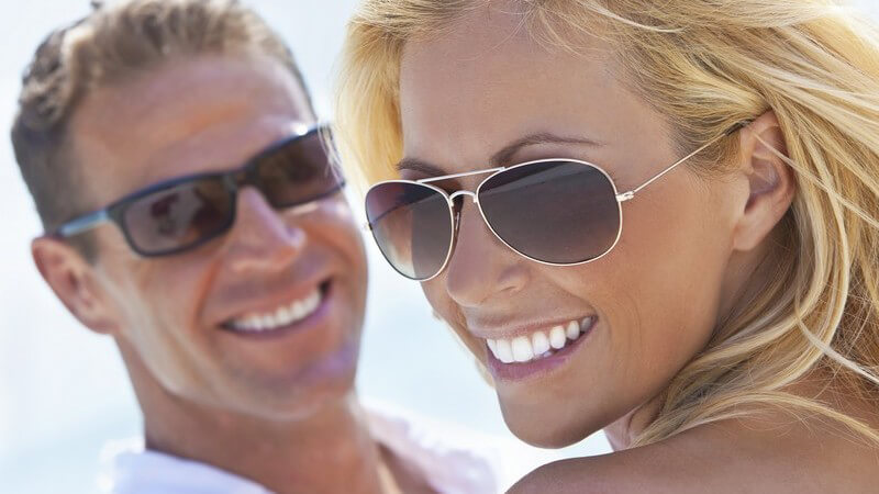 Junges braun gebranntes Paar mit Sonnenbrillen am Strand