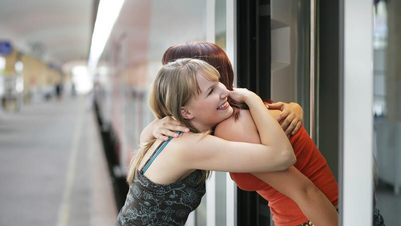 Zwei Freundinnen am Bahnhof bei Umarmung zum Abschied