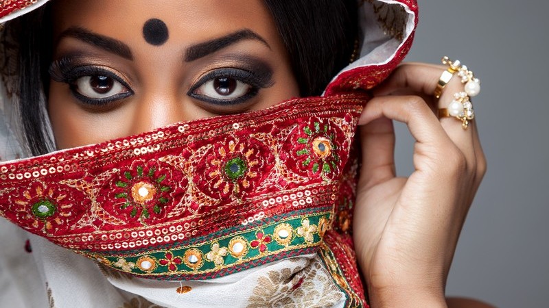 Portrait einer indischen Braut, das Gesicht halb hinter einem roten Schleier versteckt