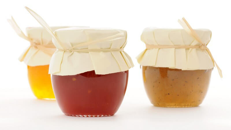 Drei Einmachgläser mit Marmelade auf weißem Hintergrund