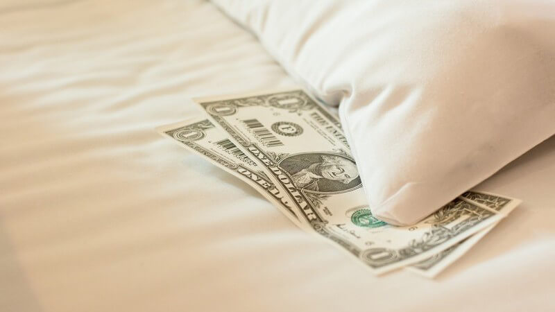 Gelscheine auf einem Hotelbett, Trinkgeld für Dienstleistung
