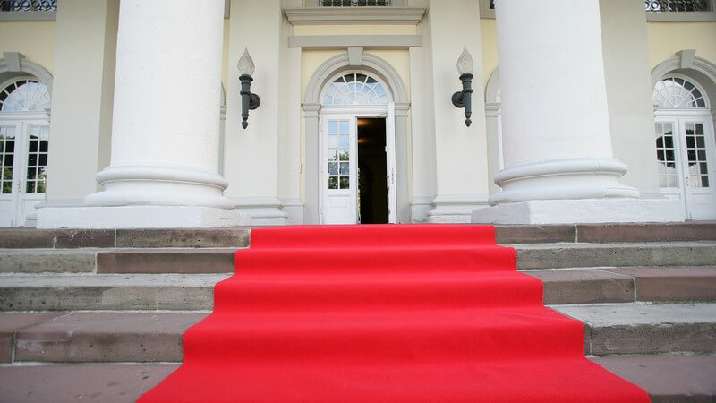 Roter Teppich auf einer kurzen Treppe vor einem prunkvollen Gebäude