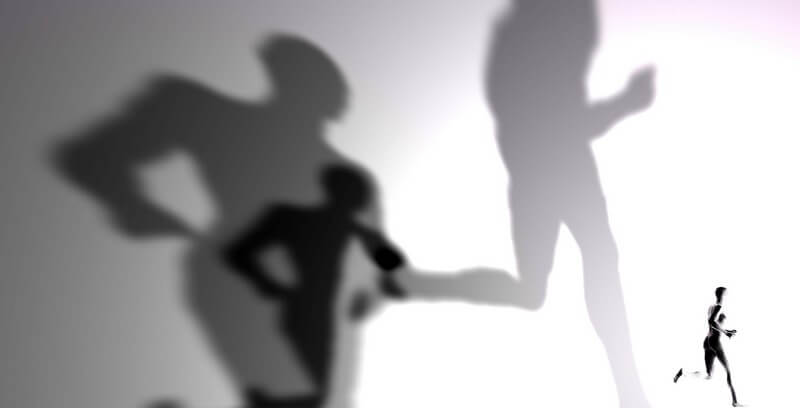 Schwarz-weiß Bild im Vordergrund kleine Gestalt beim Joggen, im Hintergrund drei riesige Schatten