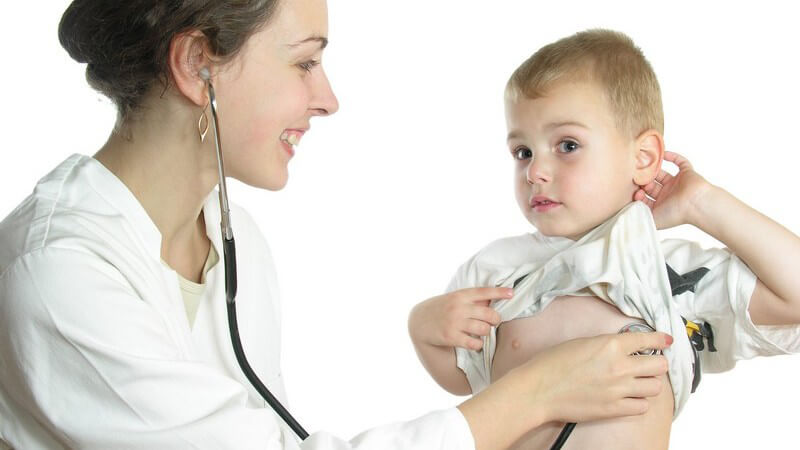 Junge, lächelnde Ärztin hört die Brust eines kleinen Jungen ab