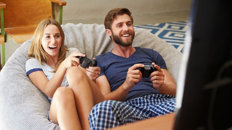 Junges Paar sitzt im Schlafanzug auf einem Sitzsack und spielt ein Videospiel