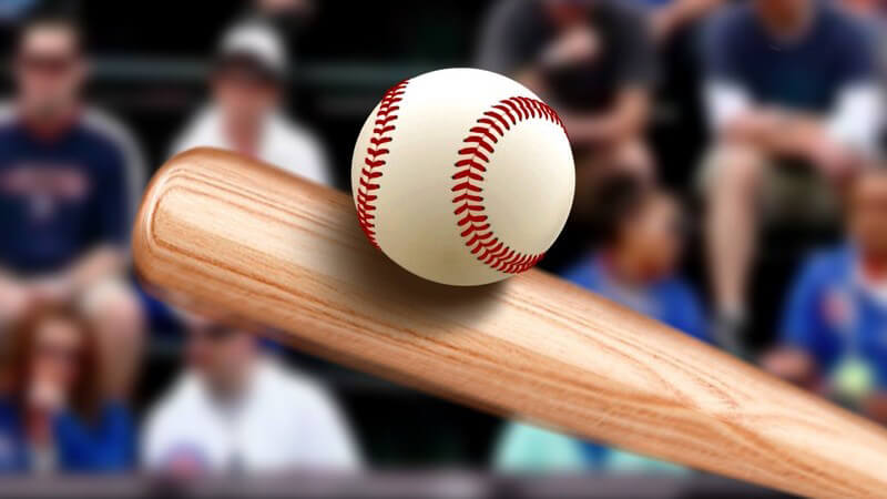 Baseballschläger aus Holz trifft einen Baseball, im Hintergrund Zuschauer