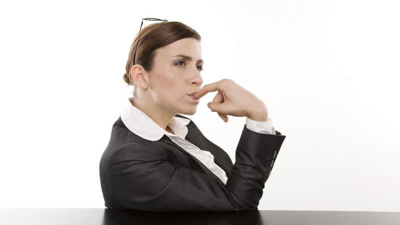 Geschäftsfrau sitzt antriebslos an Tisch, weißer Hintergrund