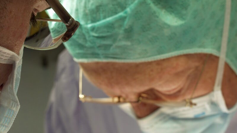 Nahaufnahme Chirurg und Assistenzärztin mit Brille bei einer Operation