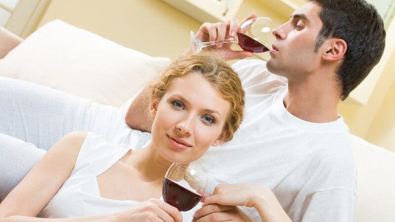 Junges Paar auf Couch mit Rotwein