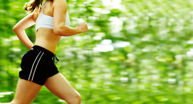Körperausschnit Frau joggt im Sportoutfit im Wald