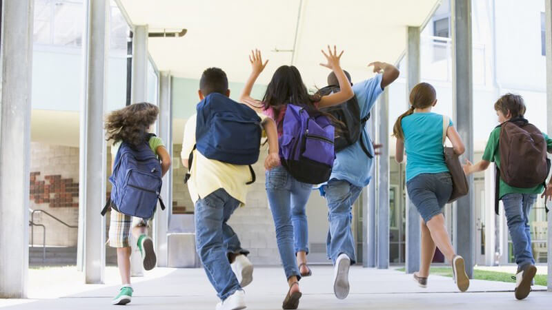 Rückenansicht sechs Schüler einer Grundschule laufen zum Ausgang