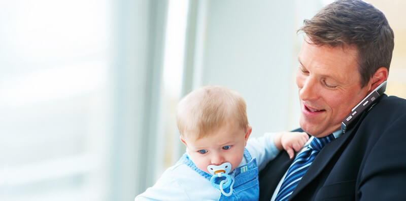 Geschäftsmann hält ein Baby auf dem Arm und telefoniert mit seinem Handy