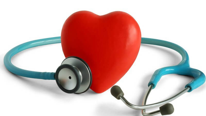 Rotes Herz aus Kunststoff, daneben Stethoskop, weißer Hintergrund