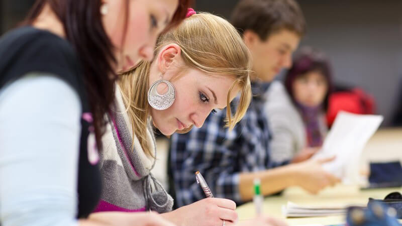 Schüler sitzen konzentriert am Tisch und schreiben