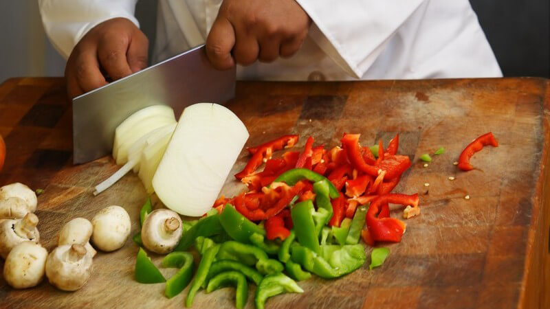 Chefkoch schneidet frisches Gemüse mit großem Messer
