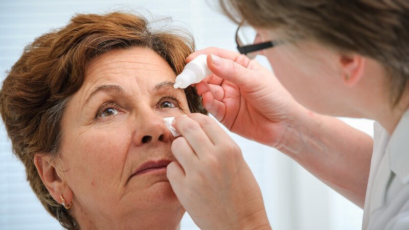 Augenärztin träufelt einer älteren Dame Augentropfen ins Auge