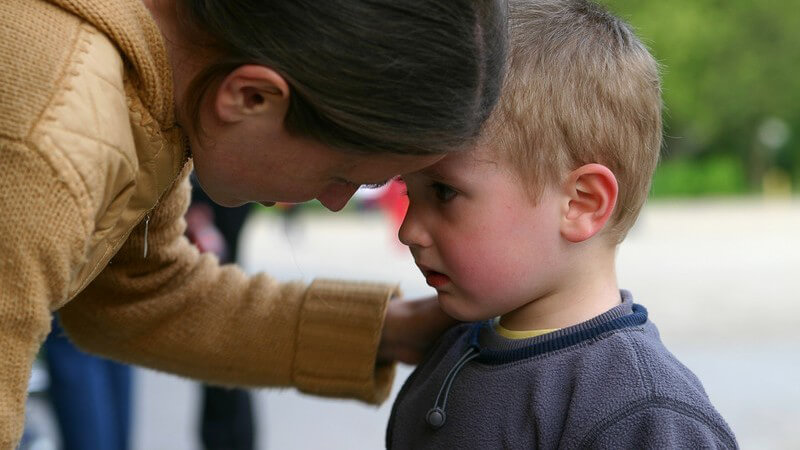 Brünette Frau tröstet kleinen Jungen mit verweintem Gesicht