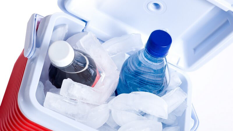 Flasche Wasser und Cola in kleiner Kühlbox mit Eis auf weißem Hintergrund