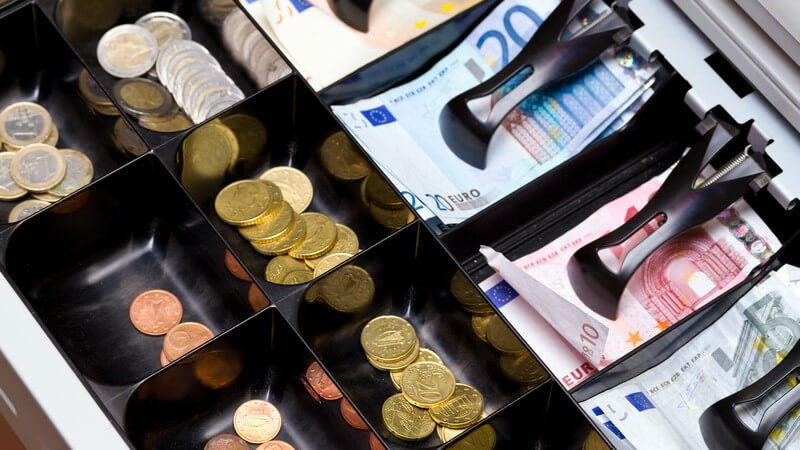Offene Geldkasse mit Euro-Münzen und -Scheinen
