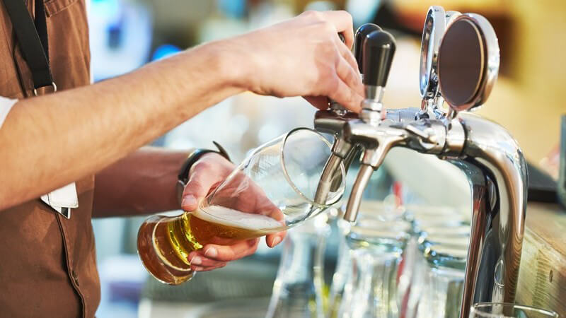 Barkeeper zapft ein frisches Bier an einer Edelstahl-Zapfanlage