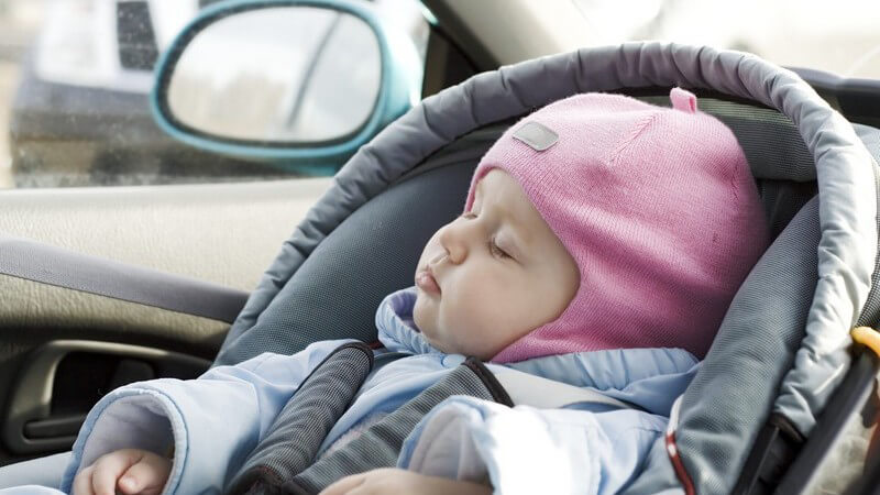 Warm eingepacktes Baby schläft im Kindersitz im Auto