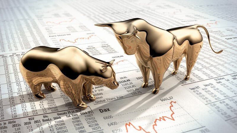 Goldener Bulle und Bär stehen auf einer Seite mit Börsenkursen