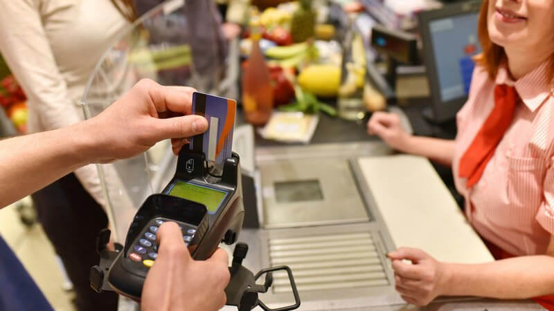Kunde steckt EC-Karte in den Kartenleser an der Kasse eines Supermarktes