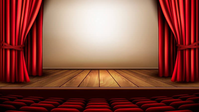 Leerer Theatersaal mit Bühne, rotem Vorhang und Sesseln