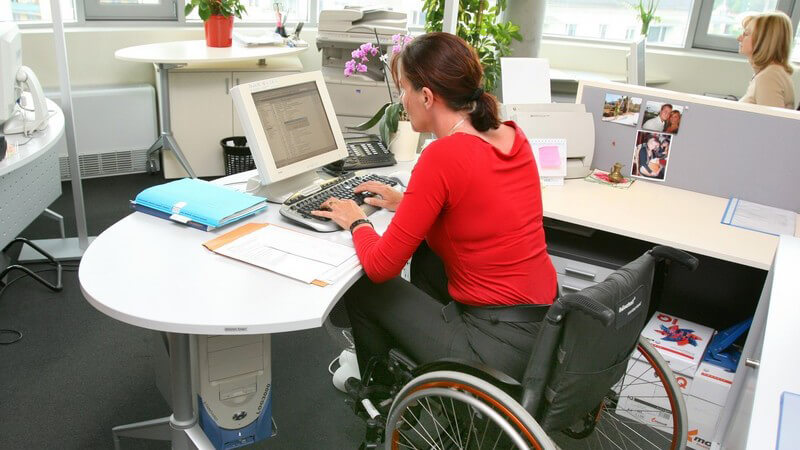 Frau im Rollstuhl am Computer im Büro
