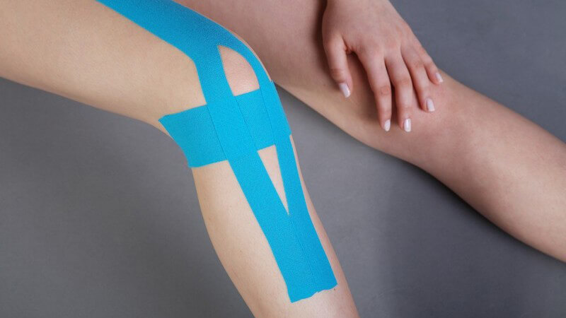 Frauenbeine, ein Kniegelenk mit Kinesio-Tape