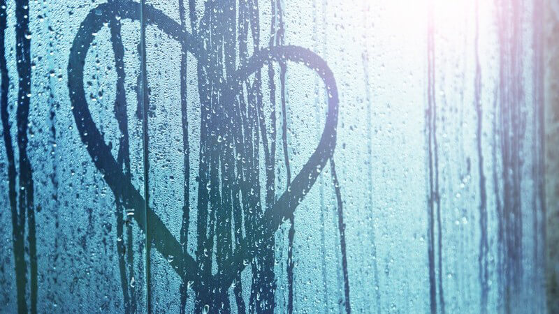 Auf Fenster gemaltes Herz, das Fenster vom Regen voller Wassertropfen