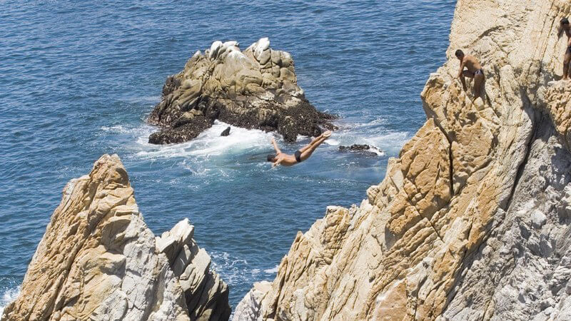 Extremsportler Springer in Acapulco am Meer, Cliff Diver springt von hohen Klippen