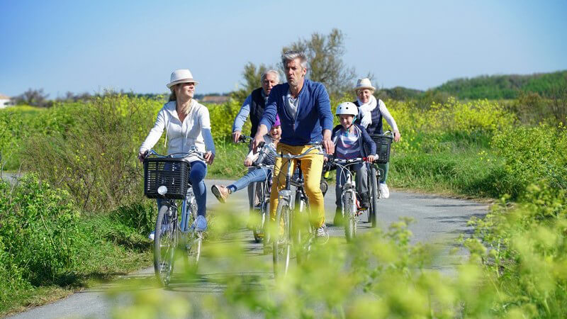 Sechsköpfige Familie mit Eltern, Kindern und Großeltern macht eine Fahrradtour durch die Natur