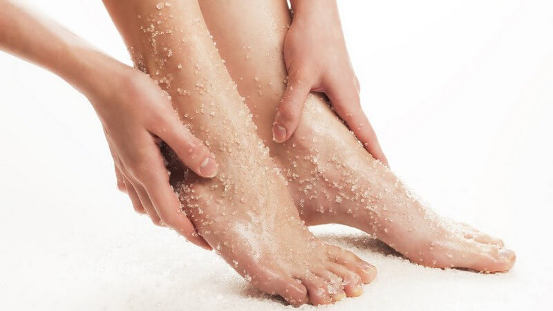 Frauenbeine mit Peeling-Salz auf Unterschenkeln und Füßen
