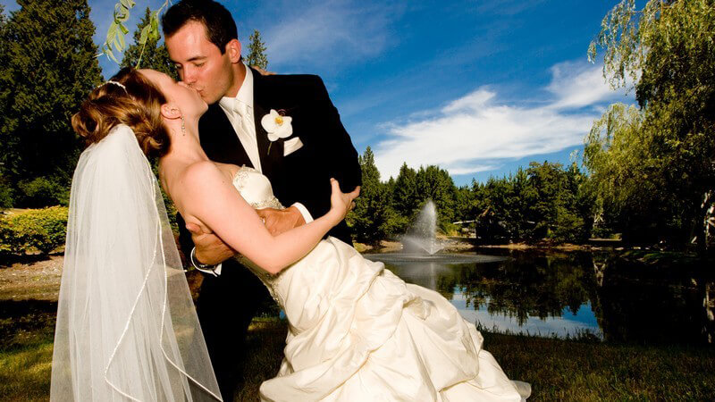 Küssendes Brautpaar, im Hintergrund schöne Landschaft