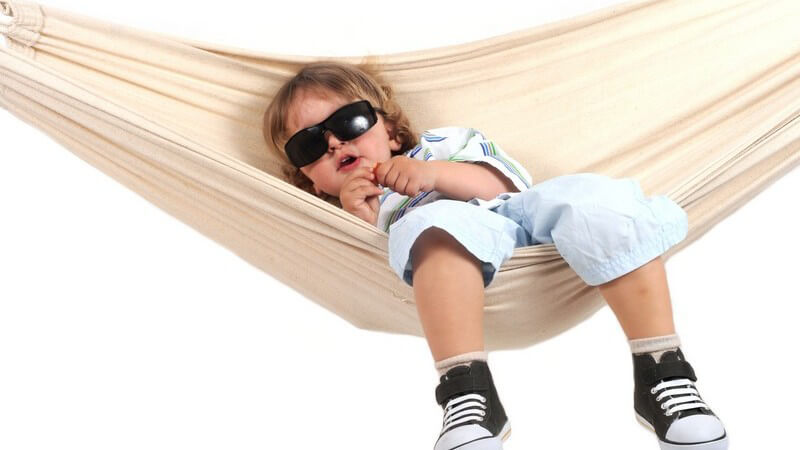Kleinkind mit Sonnenbrille sitzt in Hängematte