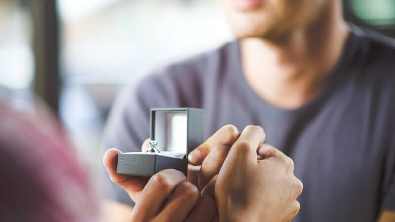 Mann packt im Cafe einen Verlobungsring aus