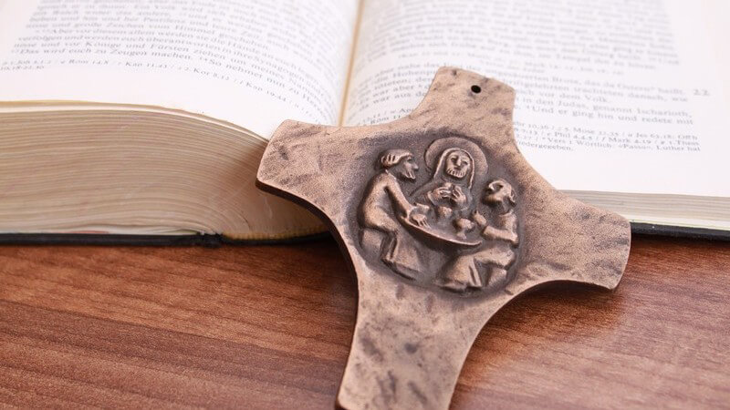 Aufgeschlagene Bibel, davor Kreuz aus Bronze