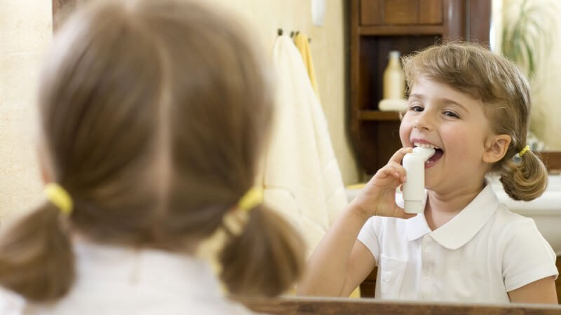 Kleines Mädchen inhaliert vor Spiegel, Asthma