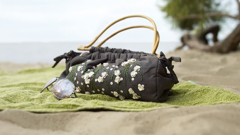 Handtasche, Sonnenbrille, Handtuch auf Strand