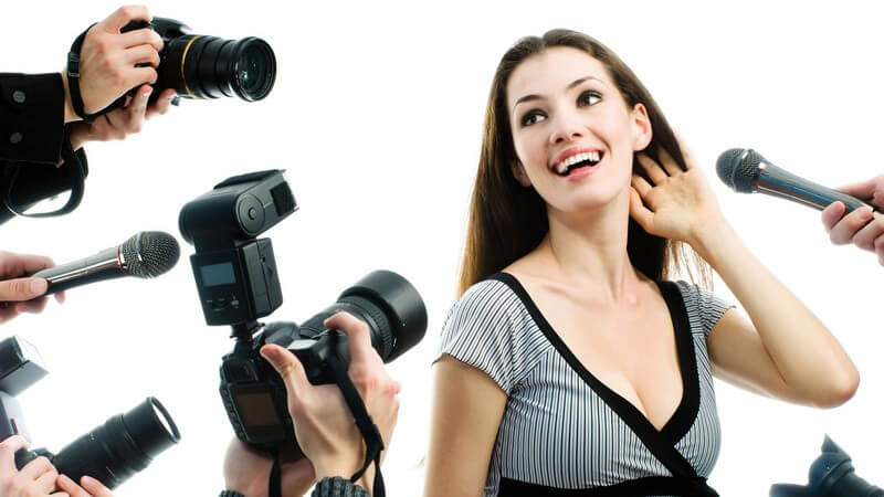 Hübsche Dame umringt von Fotografen und Mikrofonen